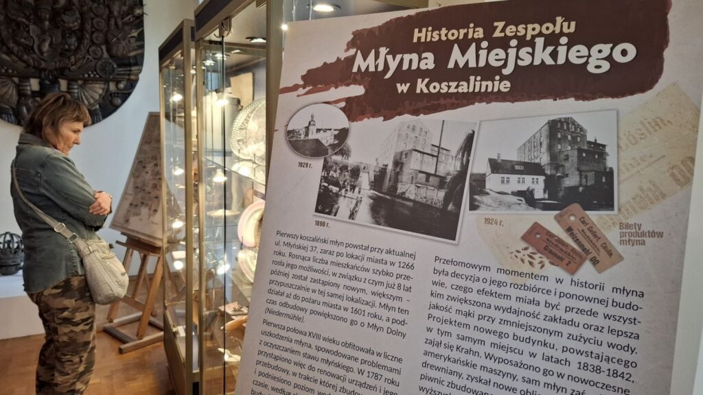Tablica informacyjna „Historia Zespołu Młyna Miejskiego w Koszalinie” na tle muzealnej ekspozycji (kliknięcie powiększy zdjęcie).