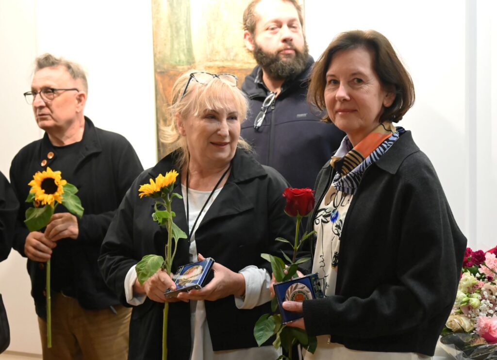 Kilka osób stoi i pozuje do zdjęcia, niektórzy z nich trzymają w ręku kwiaty (kliknięcie powiększy zdjęcie).