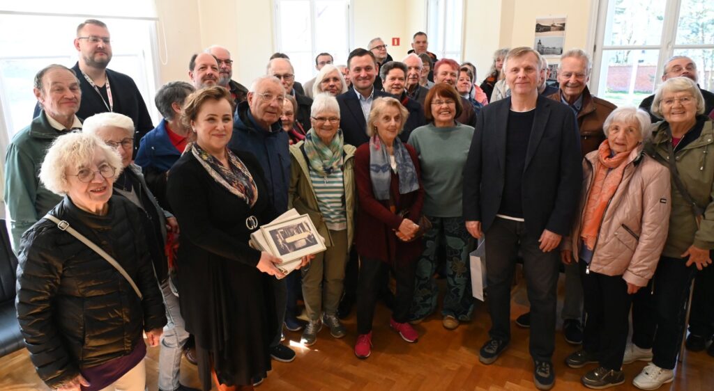 Wspólne zdjęcie grupowe uczestników wydarzenia w sali muzeum, część osób trzyma publikacje (kliknięcie powiększy zdjęcie).