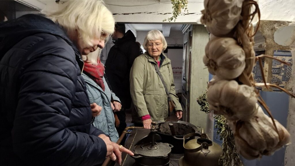 Zwiedzanie wnętrza dawnej kuchni – uczestnicy oglądają stare sprzęty i wyposażenie (kliknięcie powiększy zdjęcie).