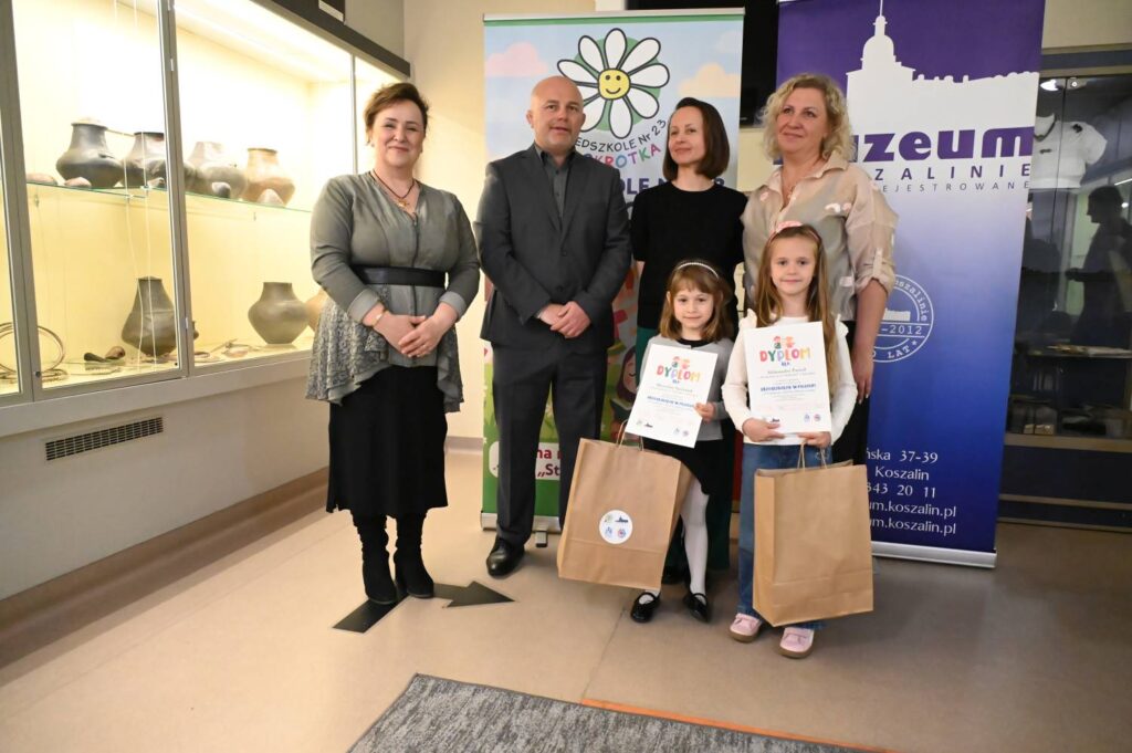 Dwie laureatki konkursu prezentują dyplomy i nagrody podczas wspólnego zdjęcia z organizatorami wydarzenia (kliknięcie powiększy zdjęcie).