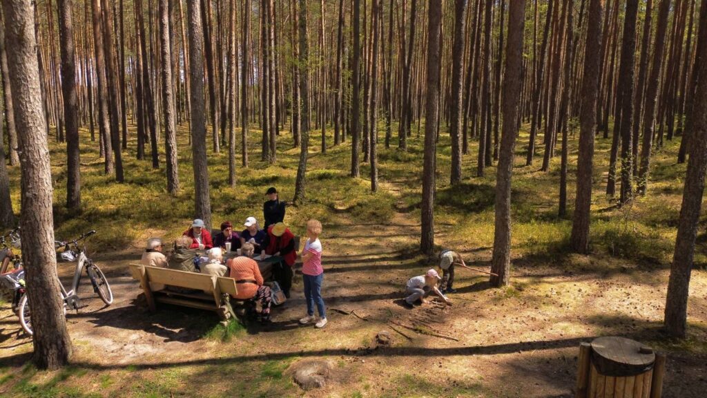 Uczestnicy akcji odpoczywają i porządkują teren wokół kamiennych kręgów w lesie w Grzybnicy (kliknięcie powiększy zdjęcie).