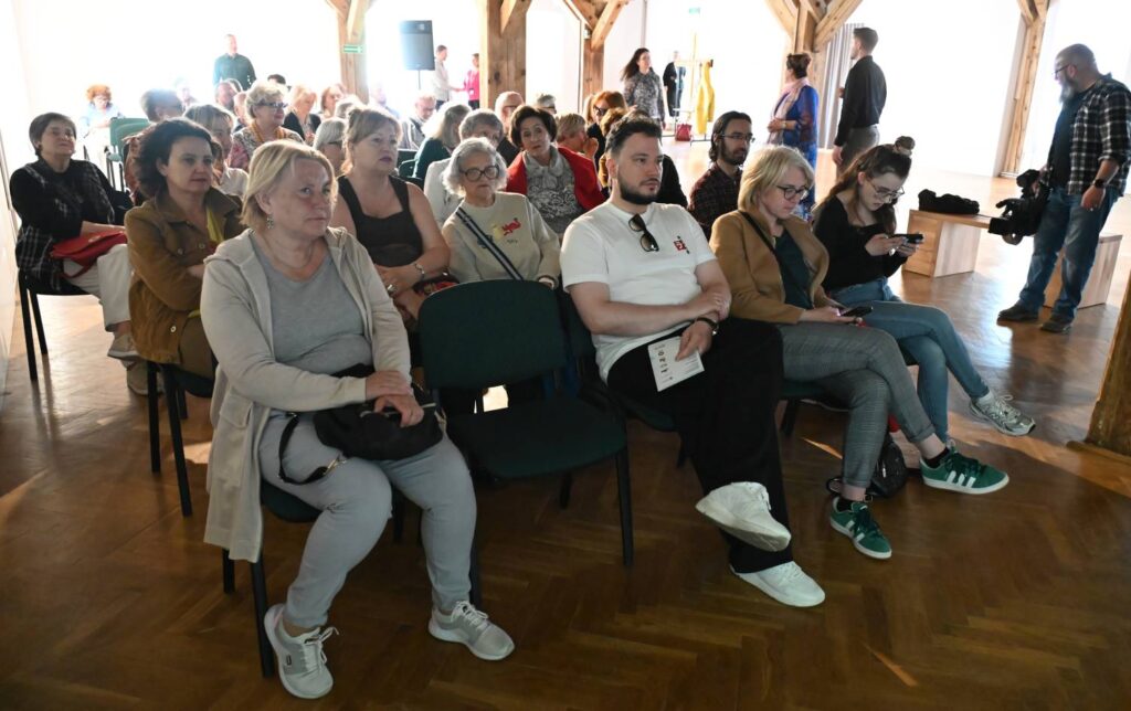Publiczność zgromadzona w sali wystawowej uczestniczy w spotkaniu towarzyszącym wystawie (kliknięcie powiększy zdjęcie).